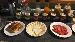 A table with food items and condiments, including jars of preserves and a plate with cheese slices. - La Casa Di Elena (Rome)