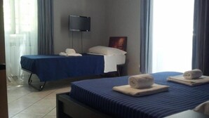 A hotel room with two beds, a flat-screen TV mounted on the wall, and a window with curtains. - La Casa Di Elena (Rome)