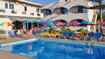 Alberca al aire libre, sombrillas en la alberca y camastros