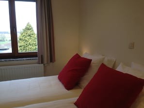 A hotel room with a bed, a window with curtains, and a radiator. - RectoVersoVV (Sint-Pieters-Leeuw)