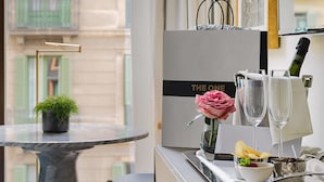 A modern hotel room with a marble table, a small potted plant, a glass of water, a bottle of champagne, and a tray with snacks. - The One Barcelona GL (Barcelona)