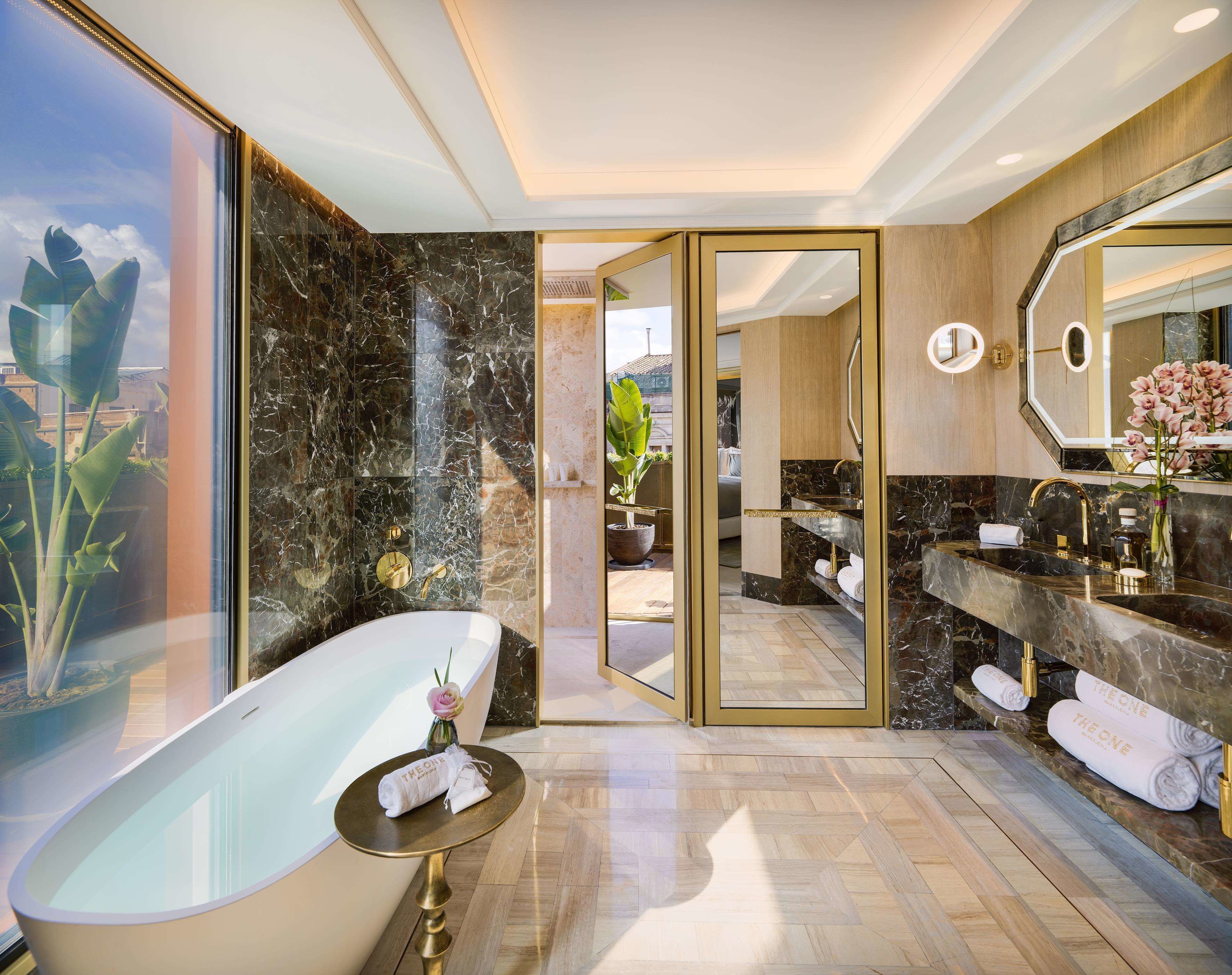 A modern bathroom with a freestanding bathtub, marble walls, and a large mirror.