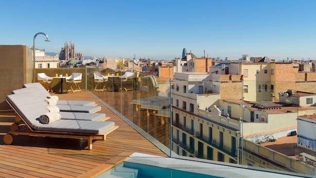 A rooftop terrace with lounge chairs and a swimming pool, overlooking a cityscape with historic buildings. - The One Barcelona GL (Barcelona)