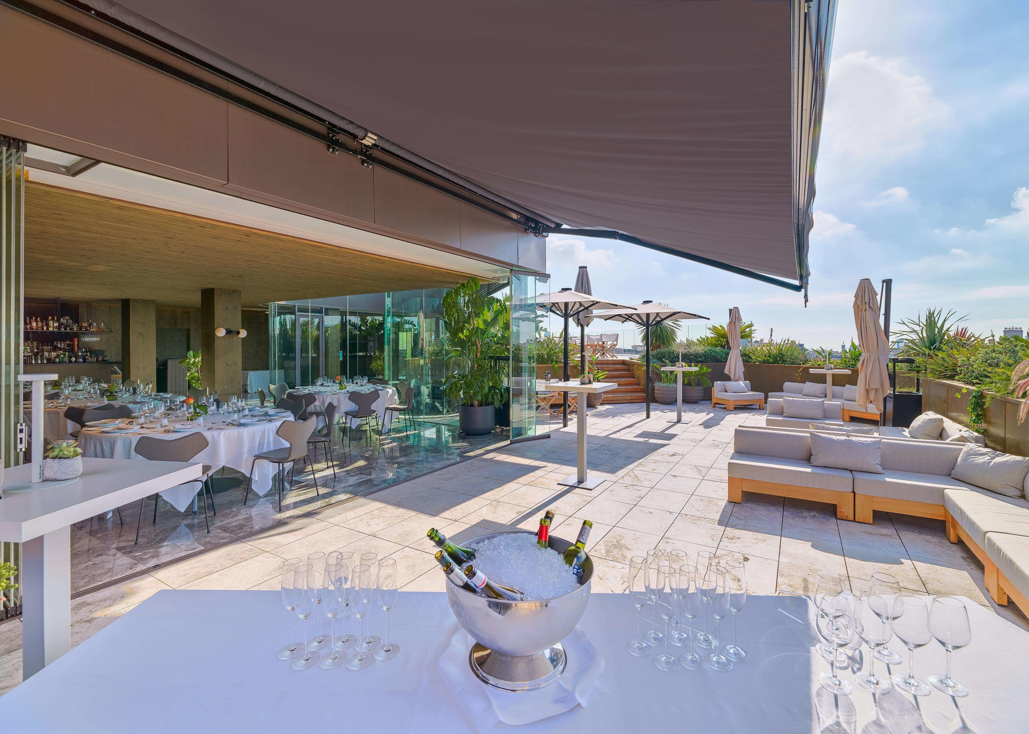 An outdoor dining area with tables and chairs, a bar area, and a seating area with umbrellas.