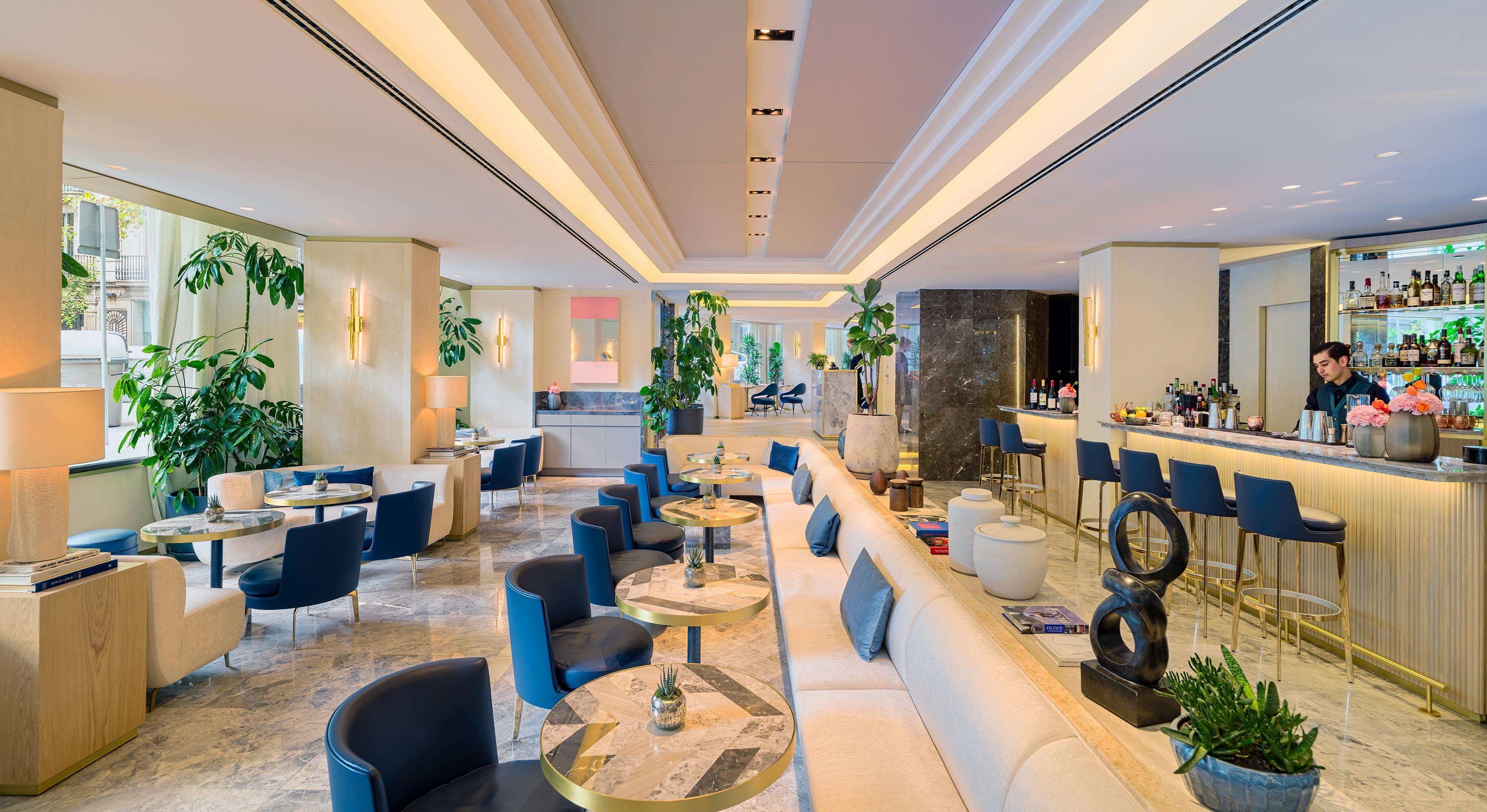 Un hall d’hôtel moderne avec des coins salon, un bar et une cuisine en arrière-plan.