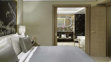 Una habitación de hotel con una cama grande, una mesita de noche, un tocador, un espejo y un baño con lavamanos y bañera.