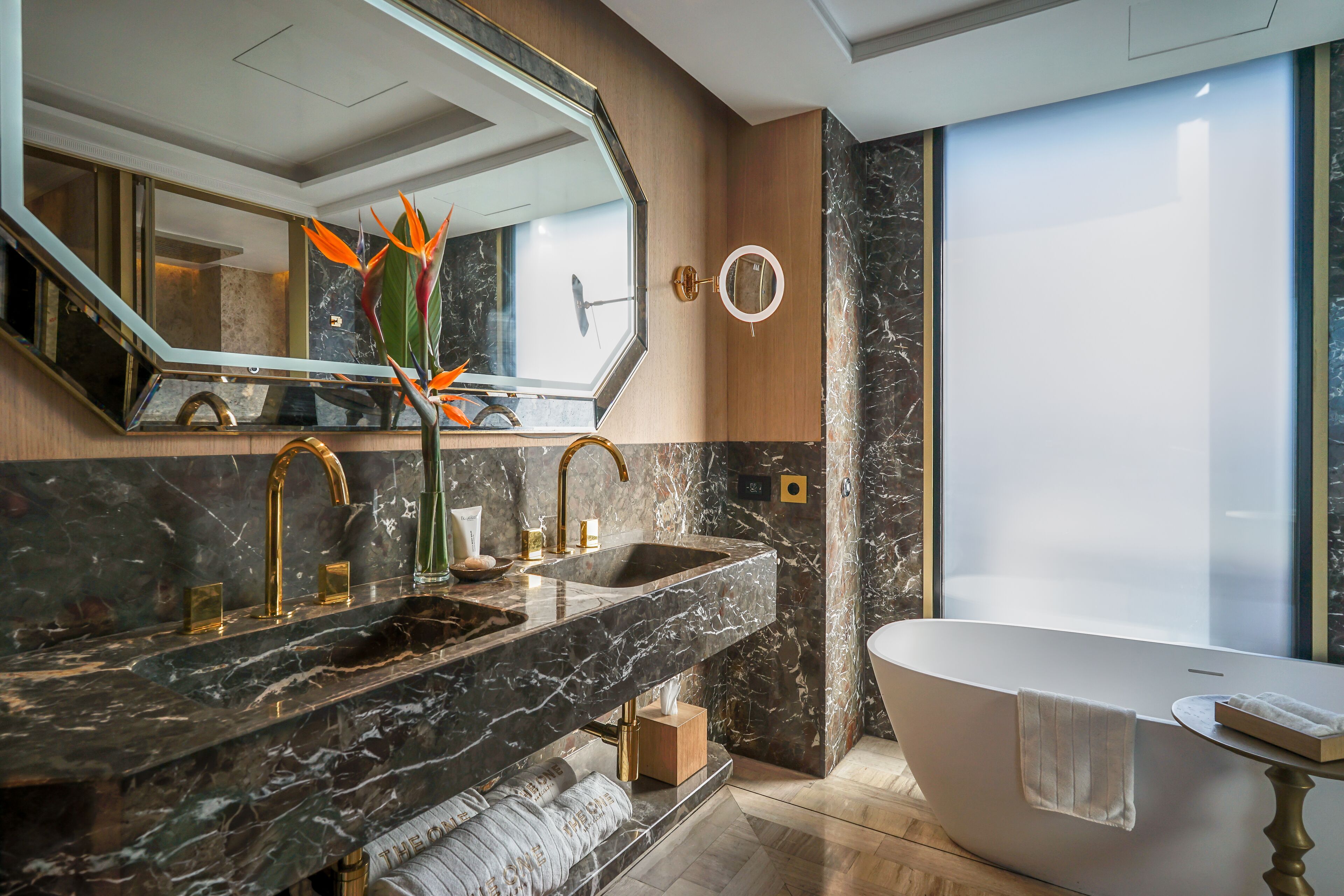 A modern bathroom with a marble sink, a freestanding bathtub, and a large mirror.