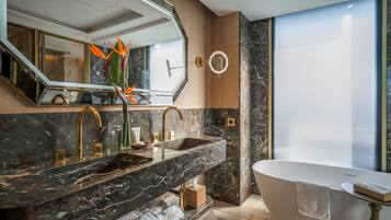 A modern bathroom with a marble sink, a freestanding bathtub, and a large mirror.