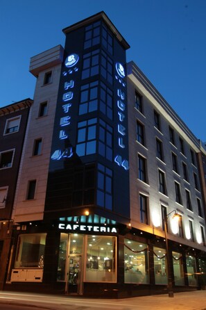 A hotel with a modern facade, large windows, and a visible restaurant named "CAFETERIA" at the ground level.