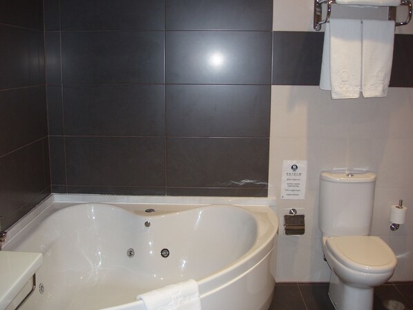 A bathroom with a bathtub, toilet, and a towel rack.