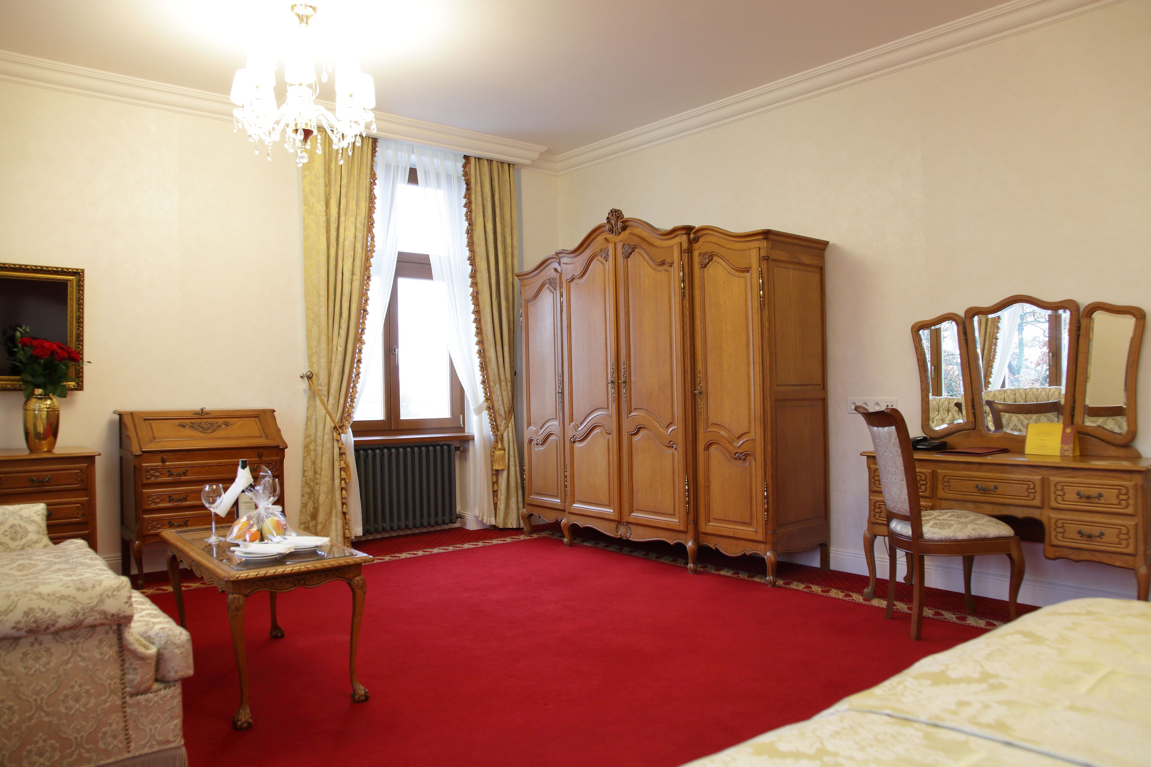 Ein Zimmer mit rotem Teppich, Holzmöbeln, einem Chandelier und einem großen Spiegel.