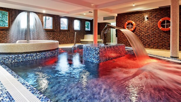 A spa area with a hot tub, a water feature, and a brick wall.