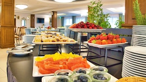 A buffet with various fruits and pastries.