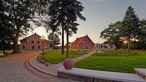 A courtyard with a paved walkway, a stone bench, and a large spherical sculpture.