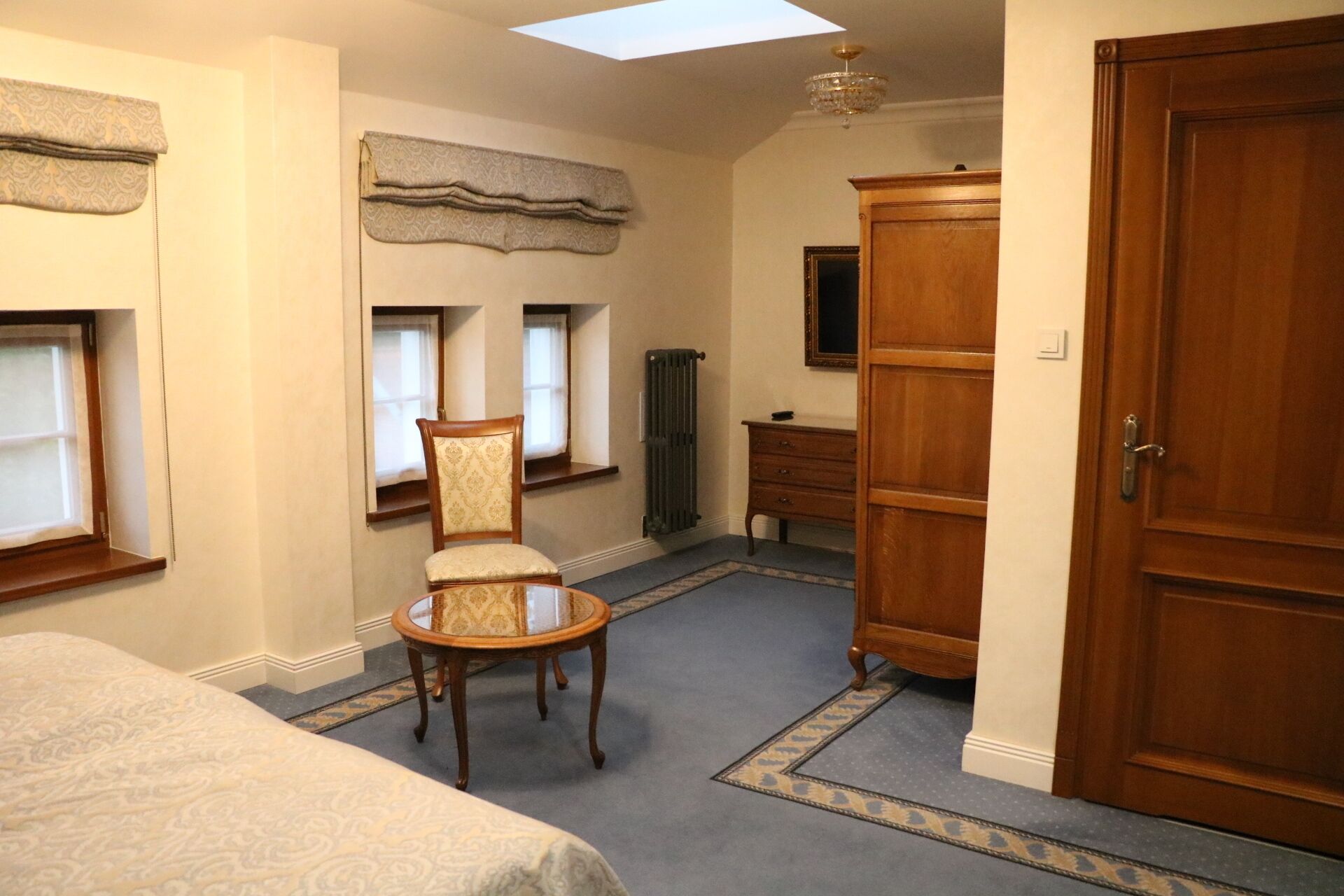 Un dormitorio con cama, una silla, un aparador y un radiador.