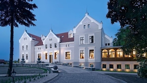 A large, multi-story building with a symmetrical facade, featuring a central entrance with steps, and a well-lit exterior.