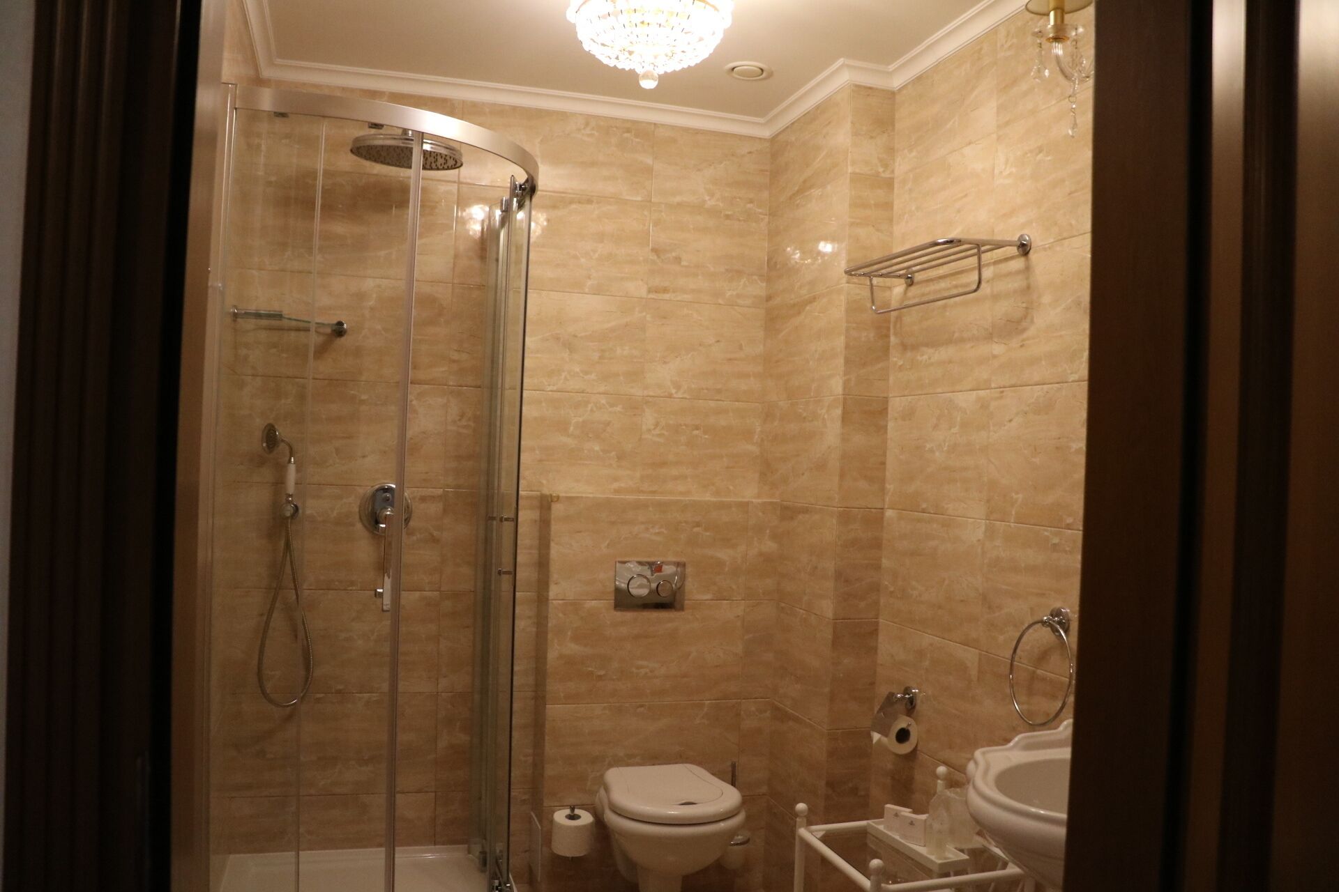 A modern bathroom with a glass-enclosed shower, a toilet, and a sink.