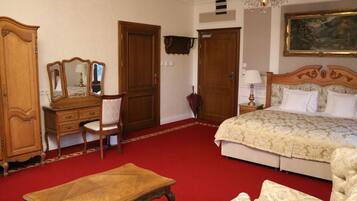 Una habitación de hotel con cama, cómoda de madera con espejo, silla, mesita y candelabro.