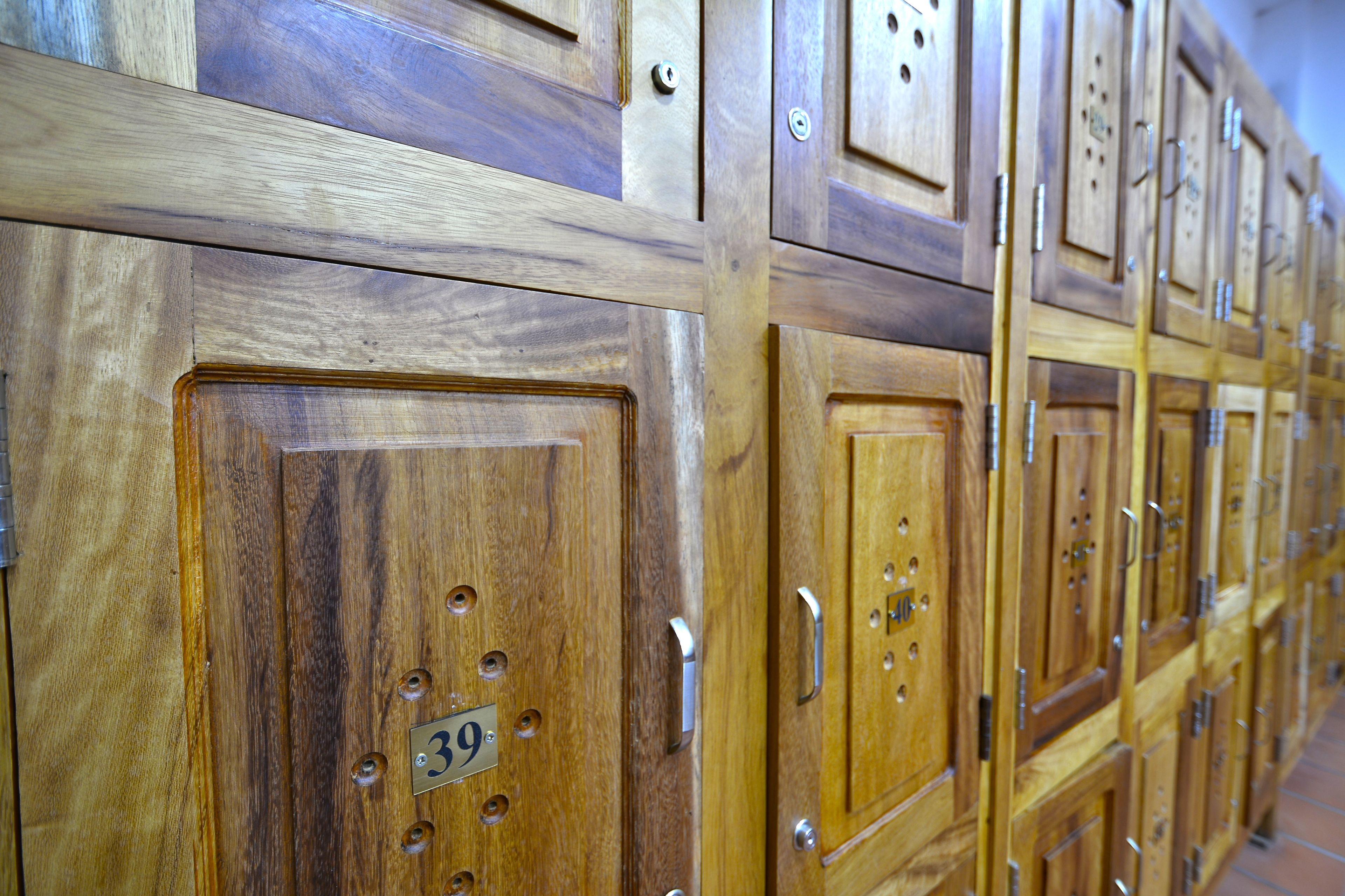 A row of wooden lockers with metal handles and numbered tags.