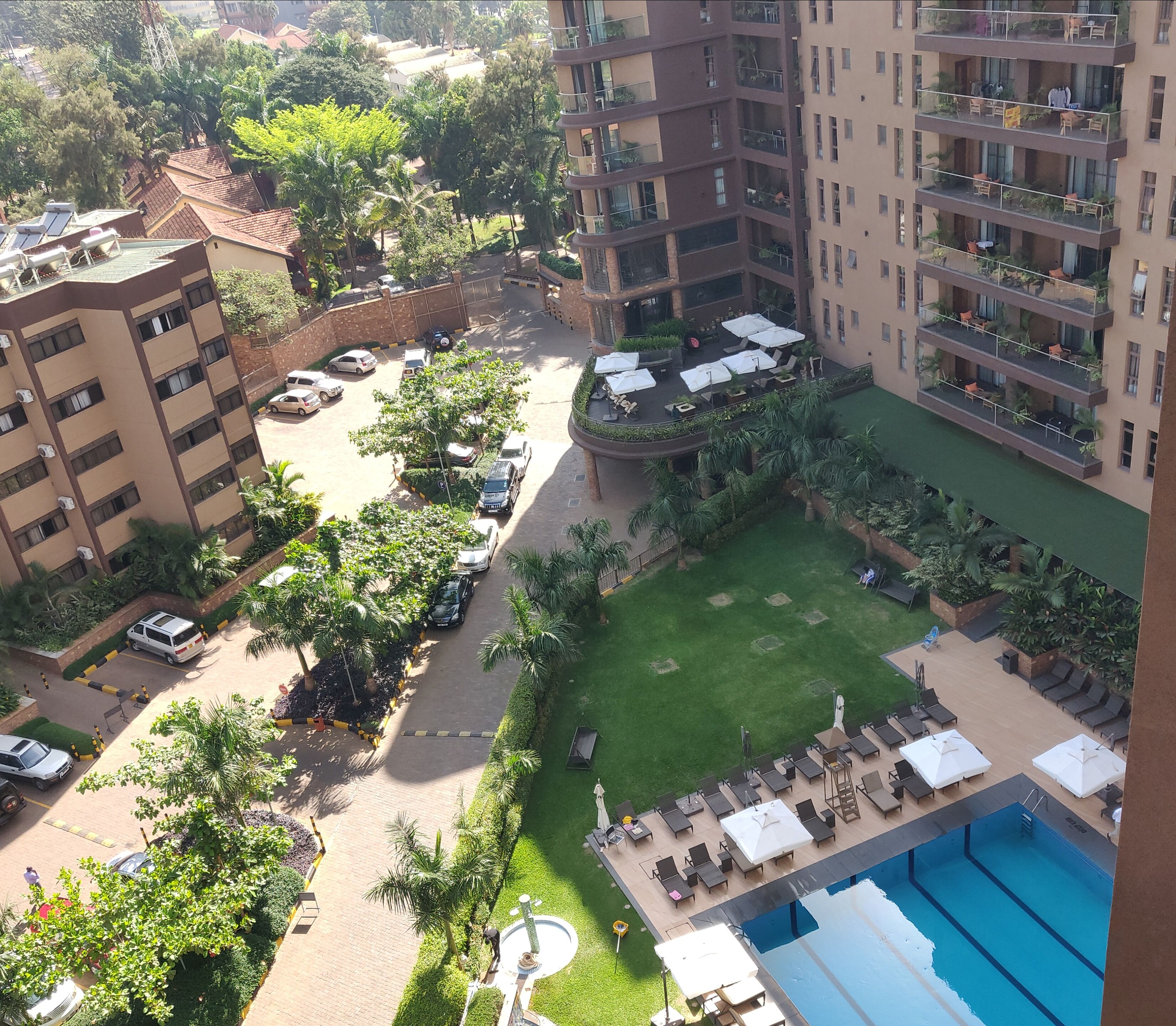 A residential building with multiple balconies, a swimming pool, and a landscaped garden area.