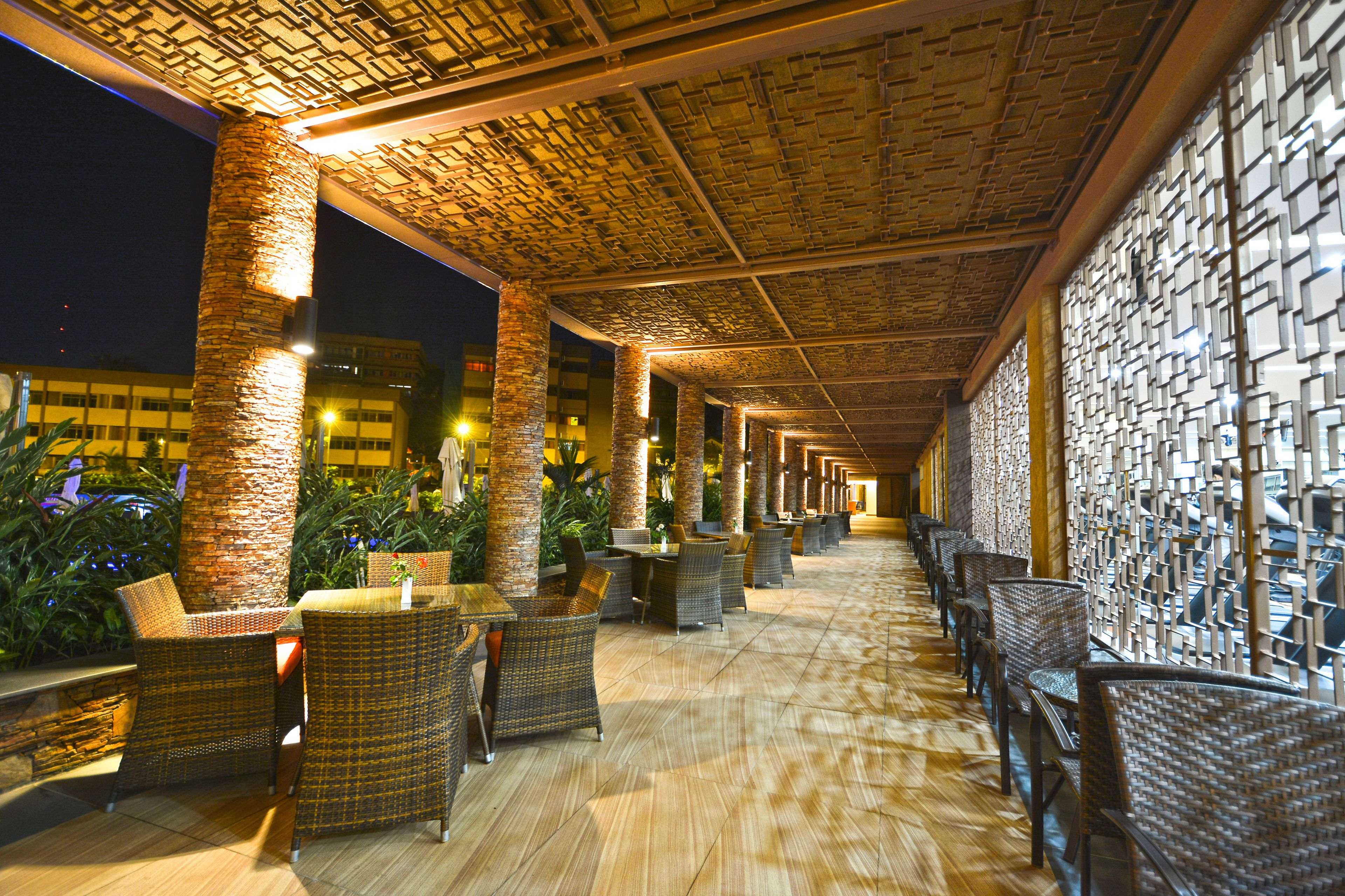 An outdoor covered area with wicker furniture and a patterned ceiling.