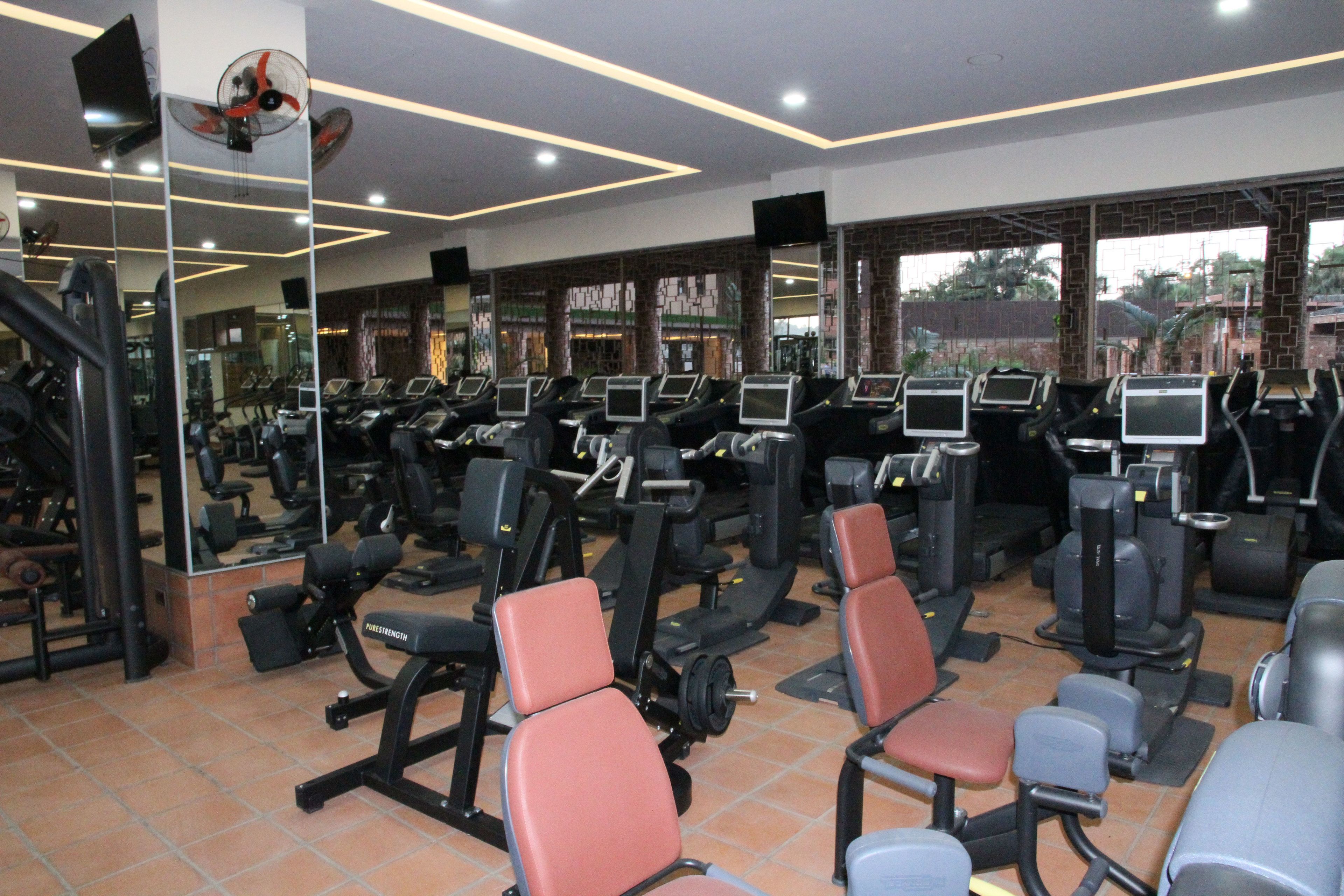 Un gimnasio con cintas de correr, máquinas de pesas y sillas de ejercicio.