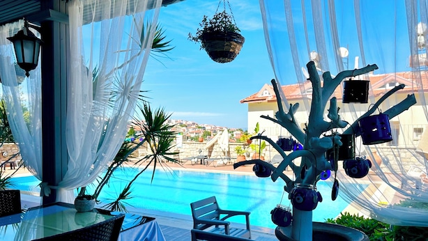 A poolside area with a view of the sea, outdoor seating, and a decorative tree structure. - Villa Anfora Otel (Datça)