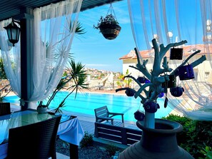 A poolside area with a view of the sea, outdoor seating, and a decorative tree structure. - Villa Anfora Otel (Datça)