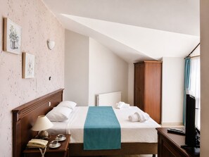 A hotel room with a bed, a nightstand with a lamp, a wooden wardrobe, and a window with curtains. - Villa Anfora Otel (Datça)