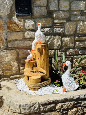 A wooden welcome sign with white pebbles and decorative ducks.