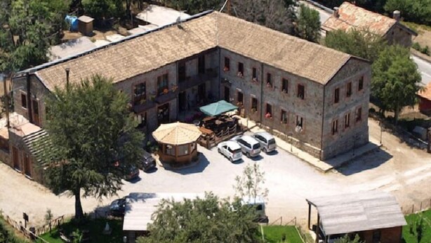 A large building with a courtyard, surrounded by trees. There are several cars parked in front, and a small gazebo in the center. - Rifugio Del Parco (San Fratello)