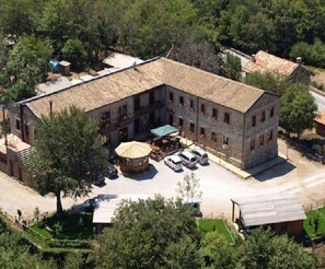 A large building with a courtyard, surrounded by trees. There are several cars parked in front, and a small gazebo in the center. - Rifugio Del Parco (San Fratello)