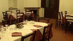 A dining area with round tables, chairs, and a fireplace. - Rifugio Del Parco (San Fratello)