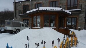 A building with a snow-covered roof and a large pile of snowshoes in front. - Rifugio Del Parco (San Fratello)