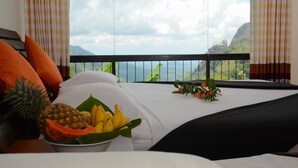 Une chambre d’hôtel avec un lit, un panier de fruits et une vue sur un paysage montagneux.
