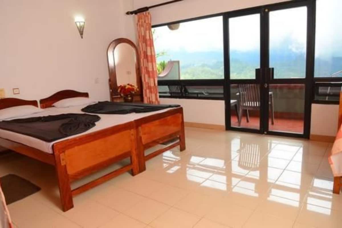 A room with two wooden beds, a large window with a view, and a balcony with chairs.