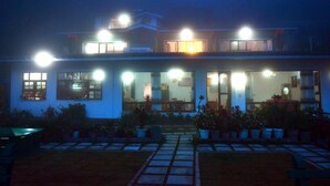 Un bâtiment à deux étages, doté de nombreuses fenêtres illuminées et d’une entrée bien éclairée.