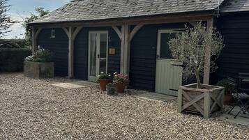 A building with a gravel driveway, wooden porch, and potted plants.