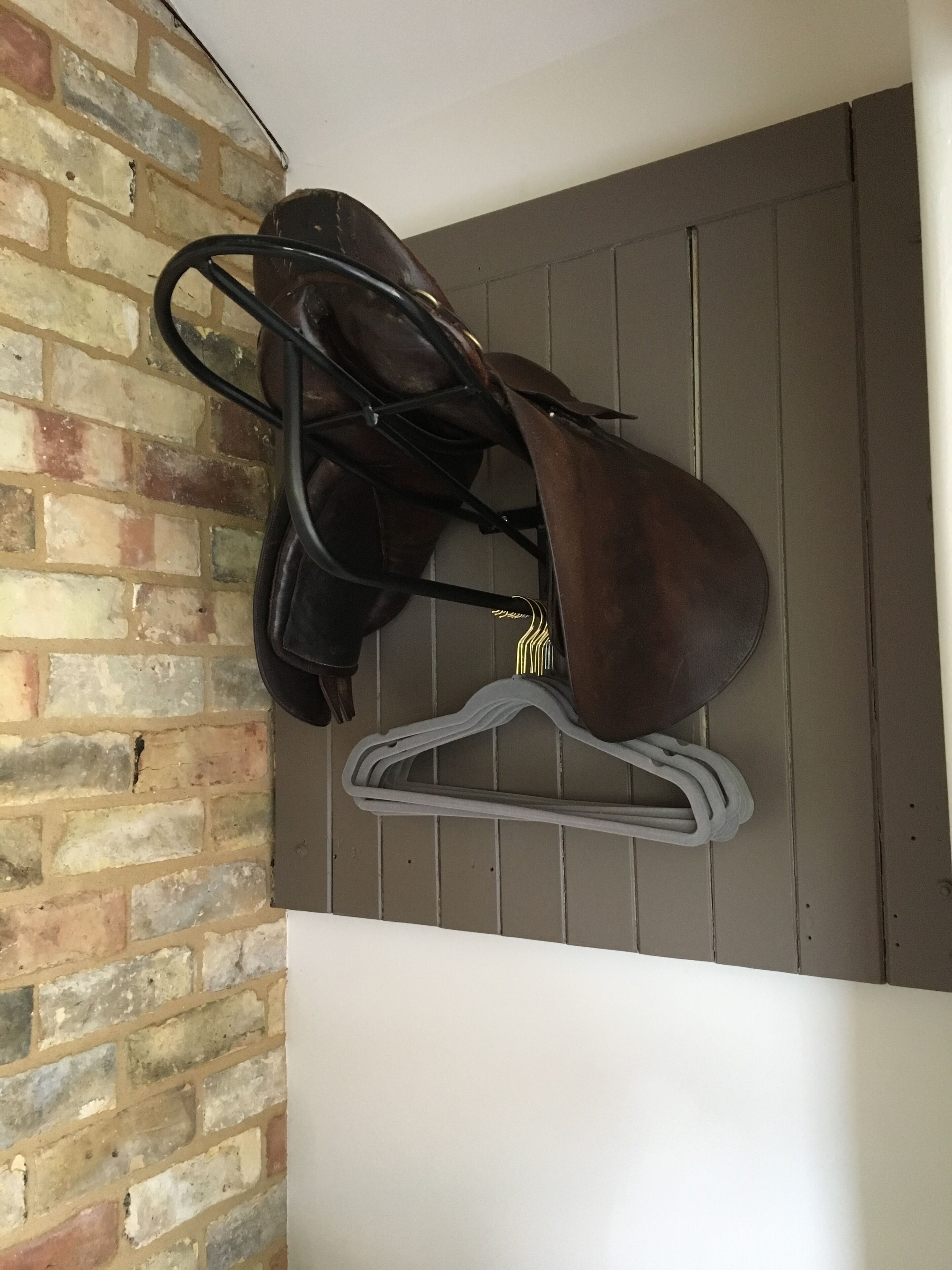 Un perchero de pared con un bolso de cuero marrón y un colgador blanco.