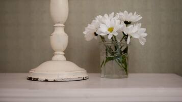 A white table with a vase of white flowers and a white candle holder.