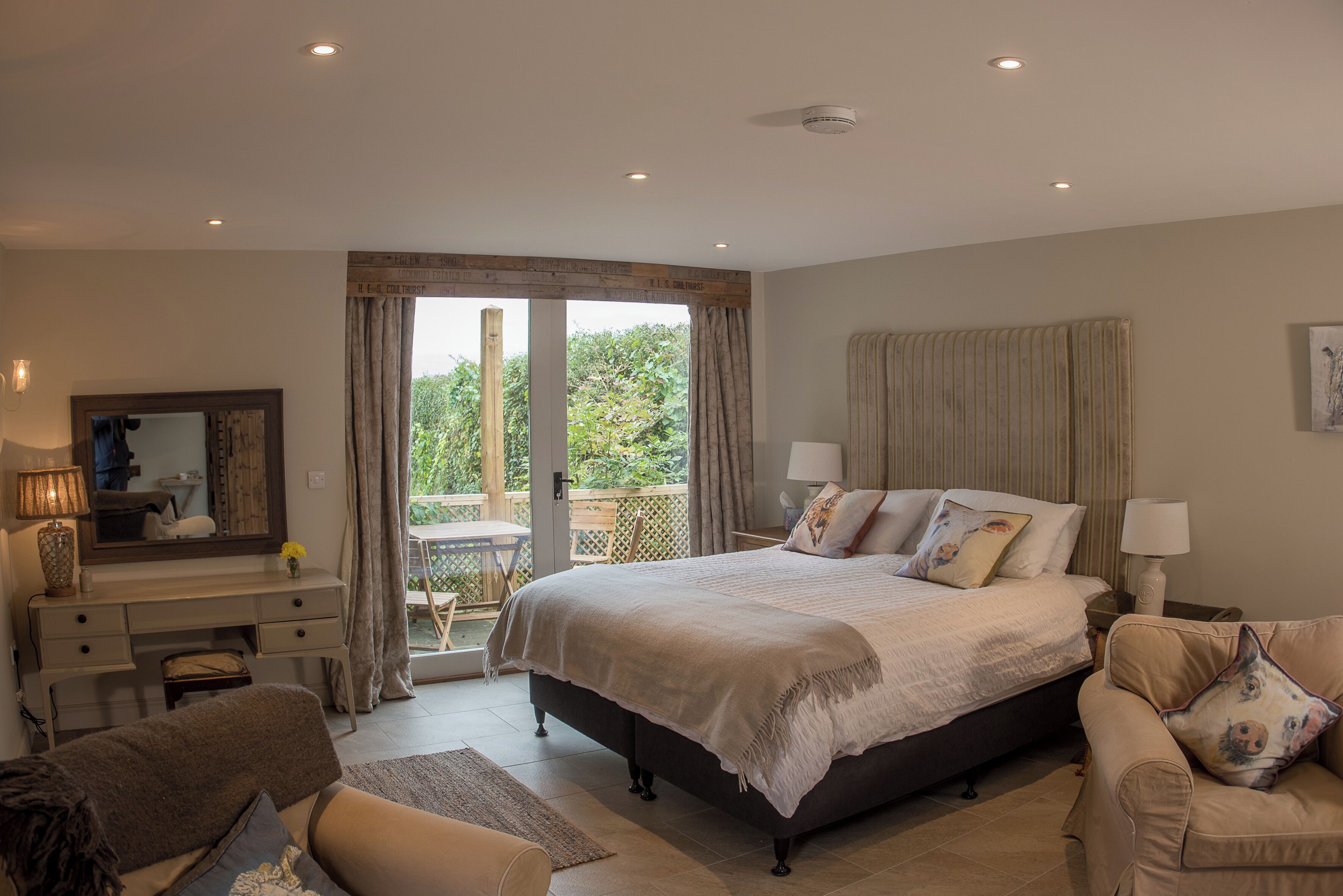 Un dormitorio con una cama grande, un escritorio, una silla y vistas al exterior.