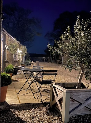 An outdoor seating area with tables and chairs, a wooden bench, and a tree. - Bridleway Bed and Breakfast (Lincoln)
