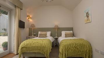 Ein Schlafzimmer mit zwei Betten, einer Kristallleuchtre, Wandlampen, einem Gemälde und einem Fernseher an der Wand.