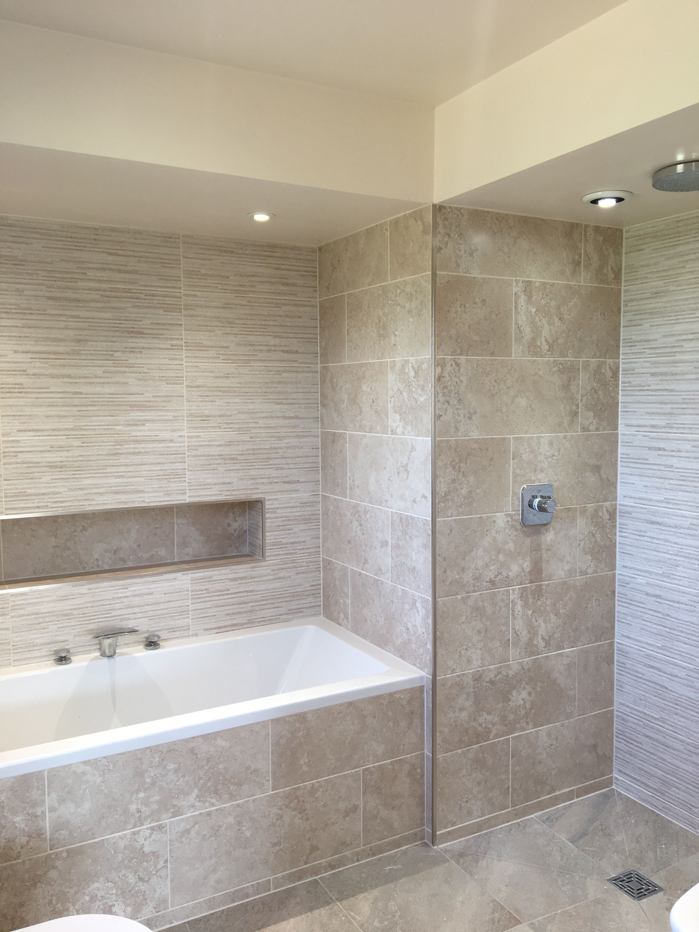 Une salle de bain moderne avec une baignoire sur pieds, un espace douche et un miroir fixé au mur.