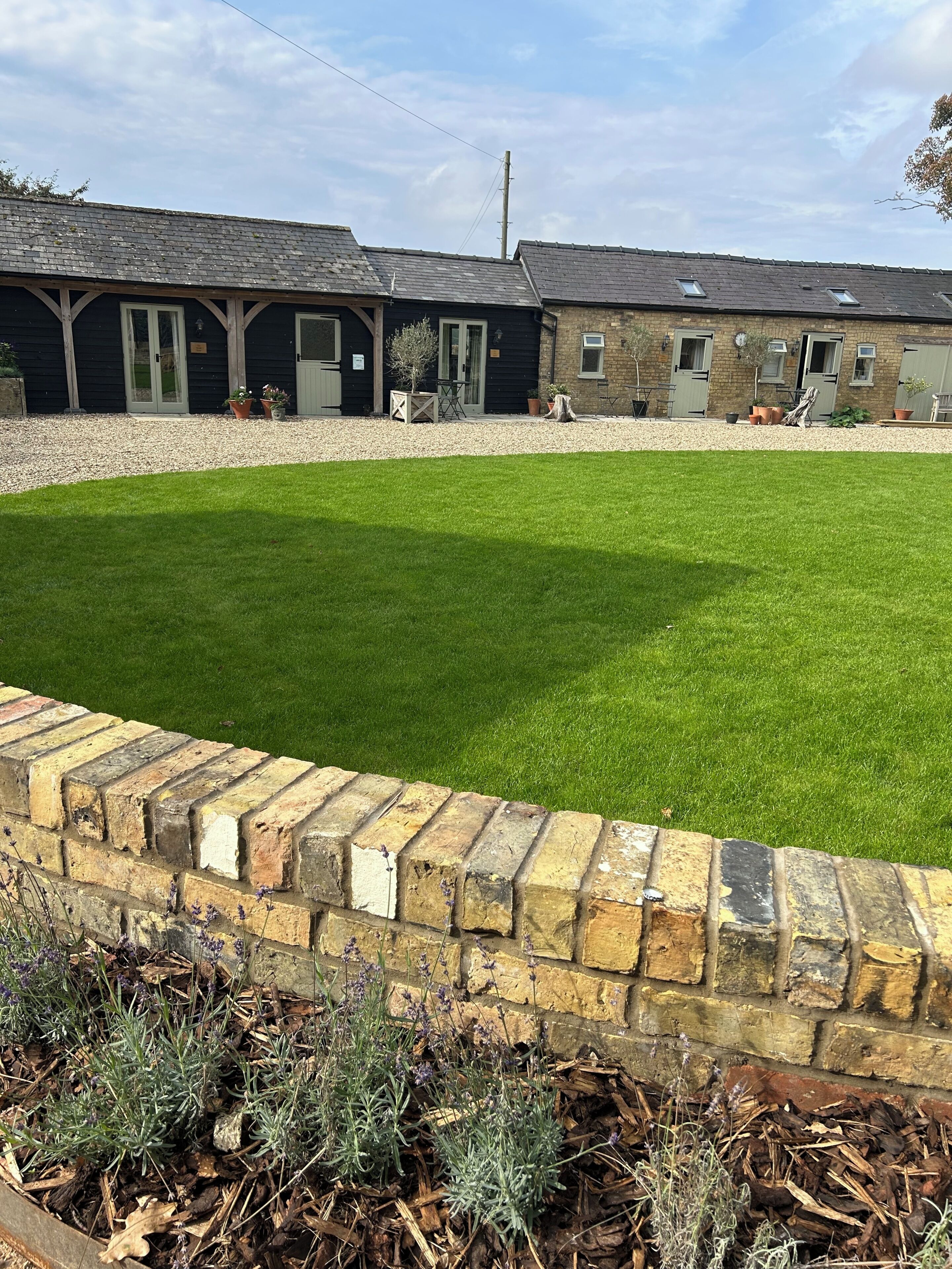 A well-maintained lawn with a brick border, a building with multiple doors and windows, and a gravel path.