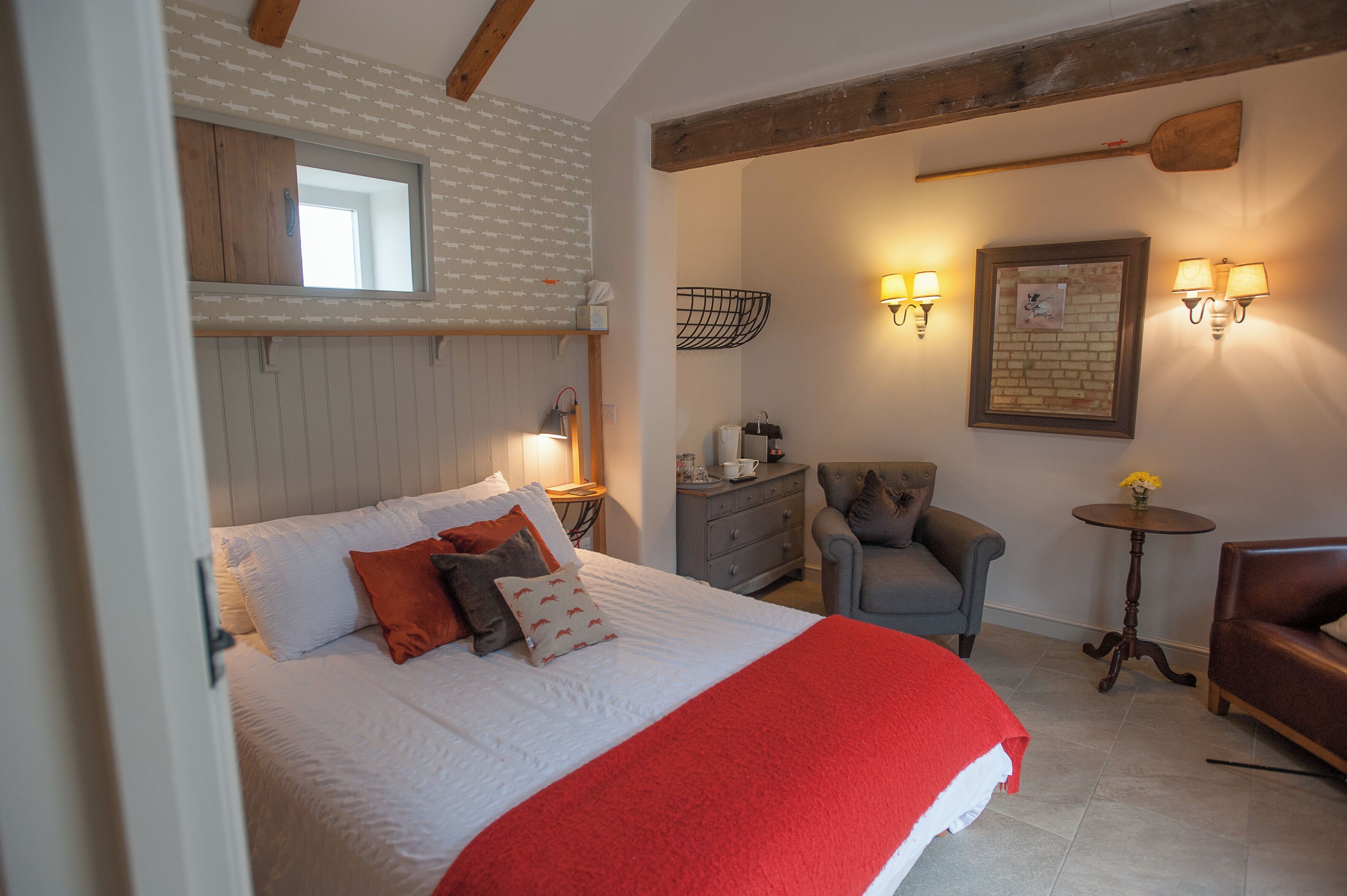 Une chambre à coucher avec un lit, une chaise, une petite table et une lampe fixée au mur.
