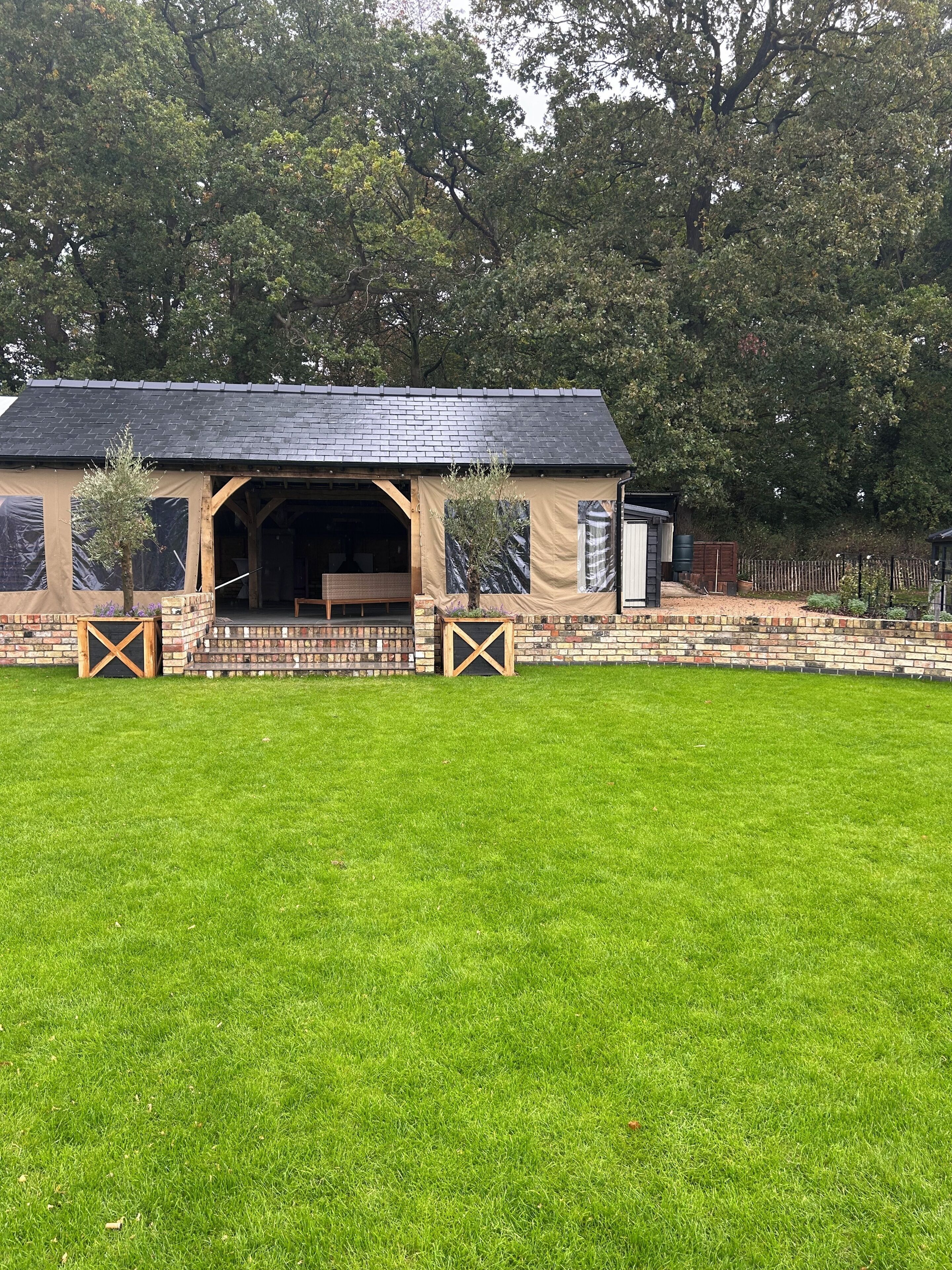 A covered outdoor area with a brick wall and a wooden bench.