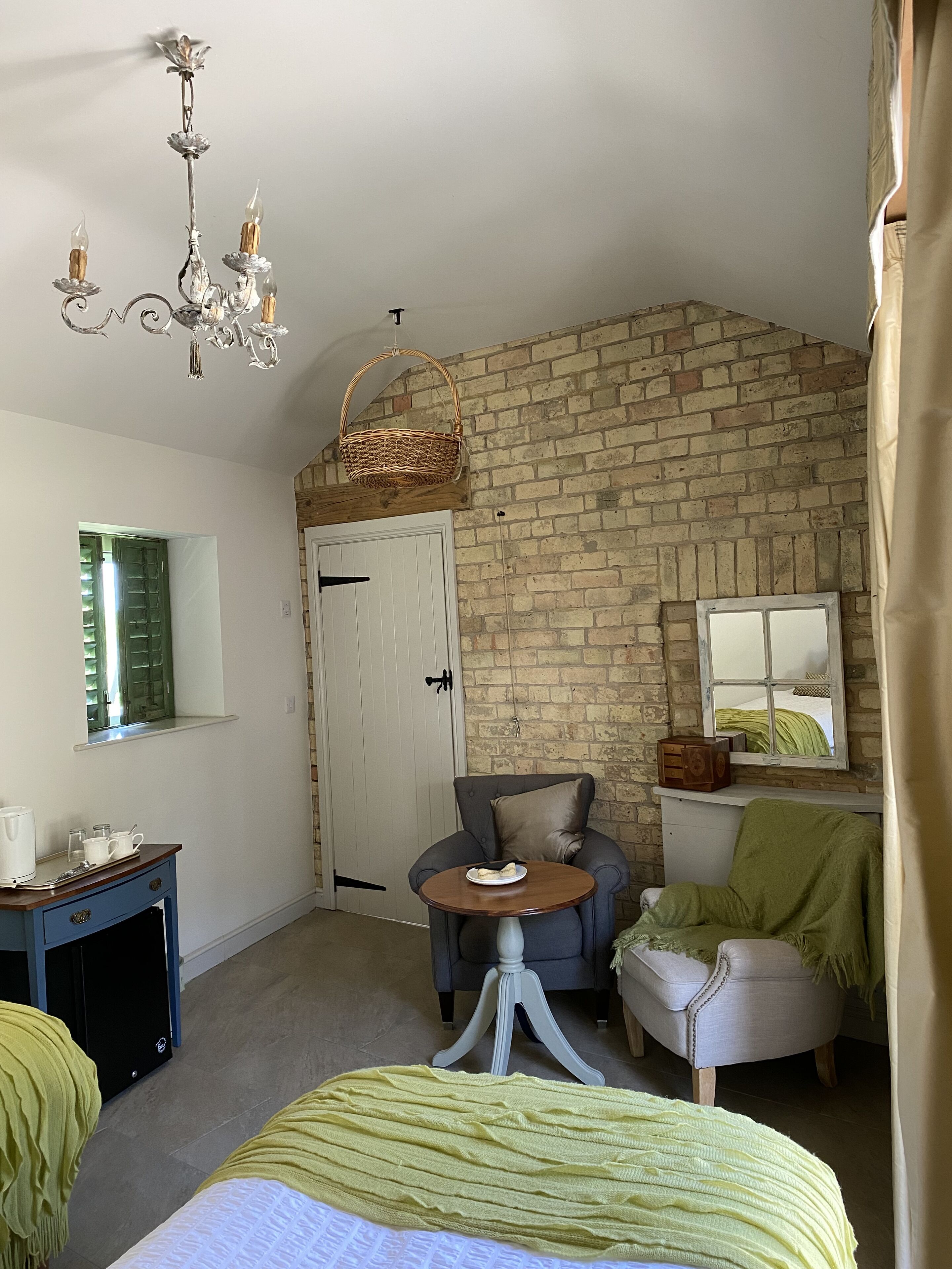 Une pièce confortable avec un lit, une chaise, une petite table, un bureau et un mur en briques.