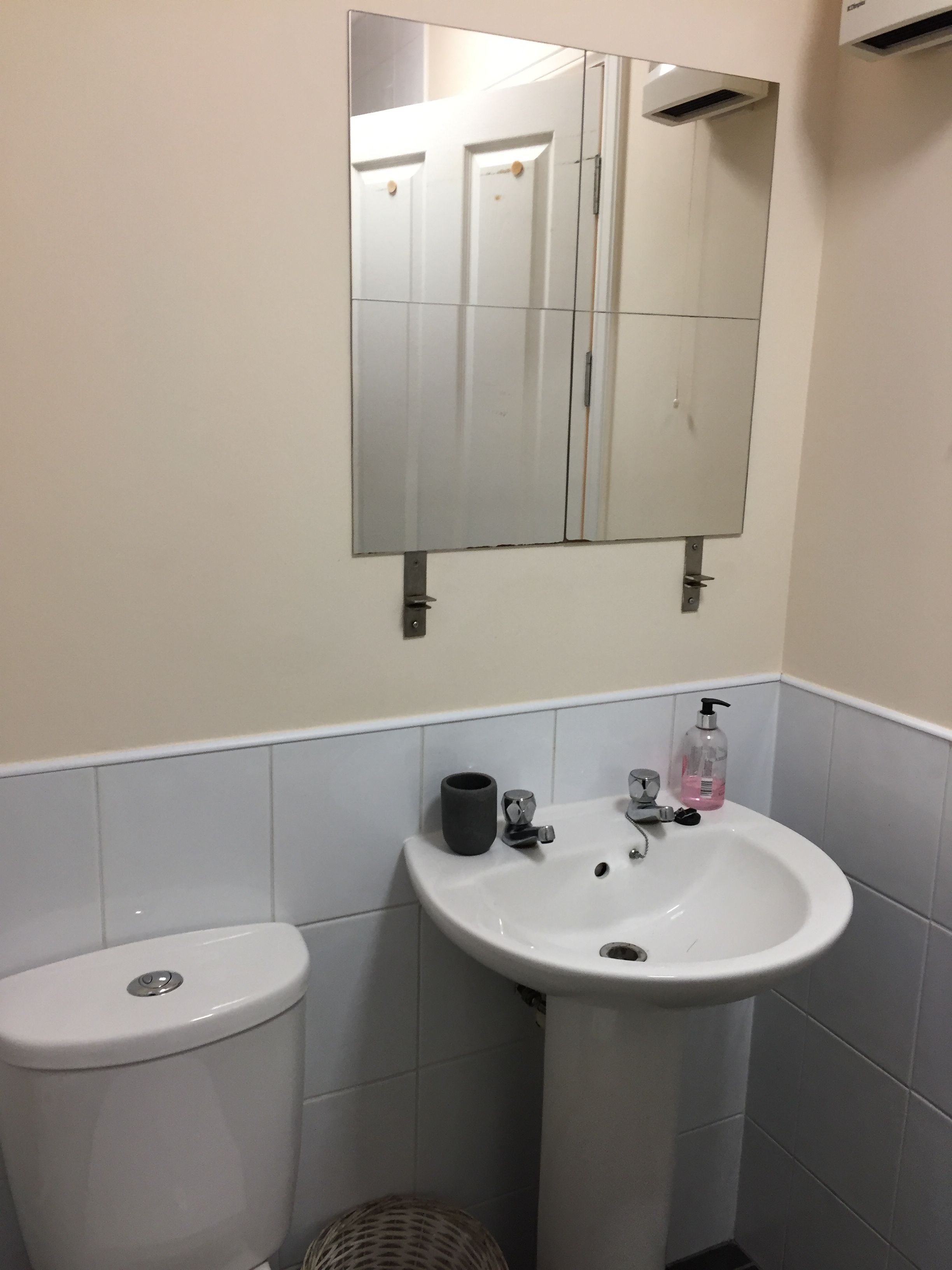 A bathroom with a white sink, a mirror, and a toilet.
