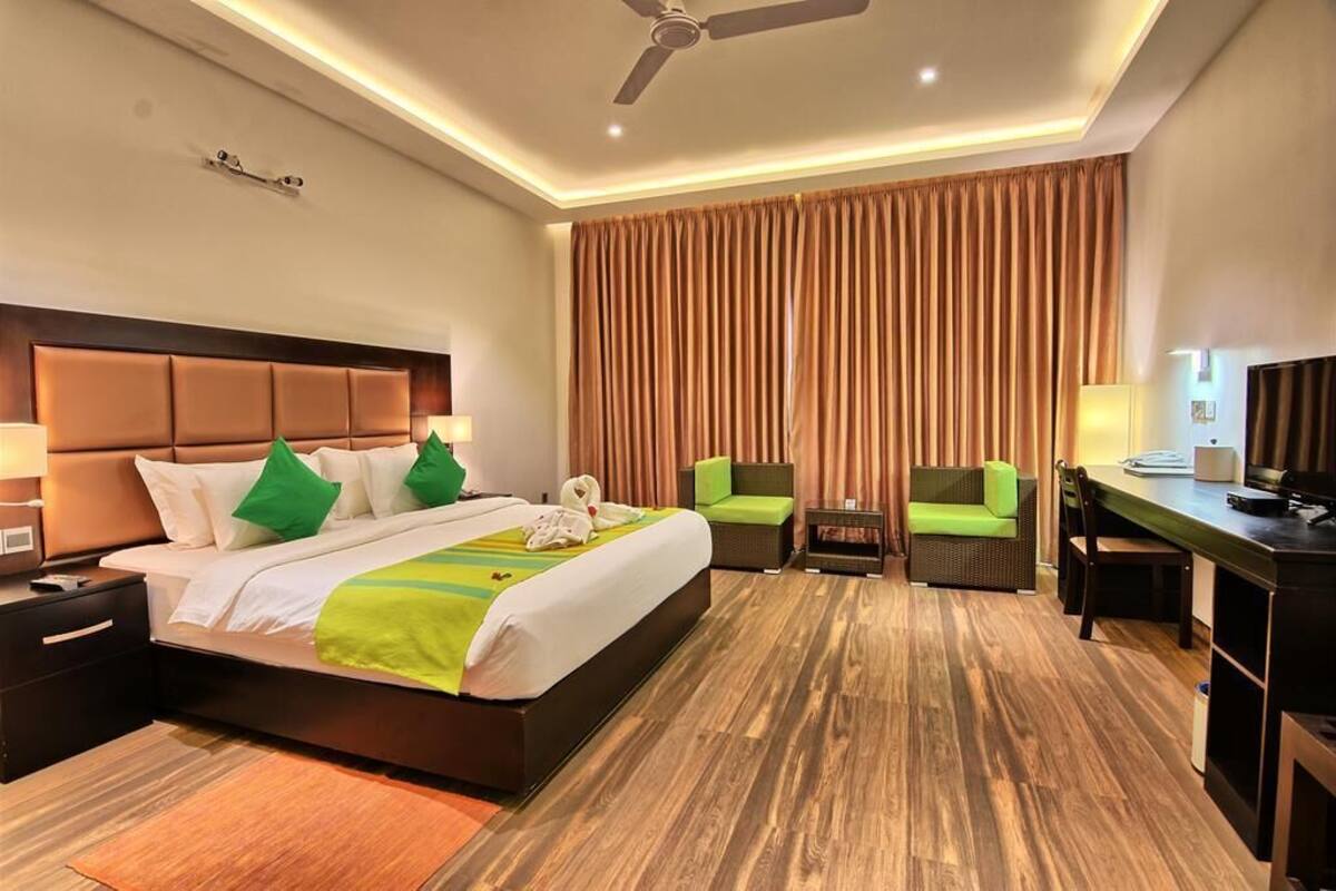 A hotel room with a large bed, a desk, a chair, and a television.